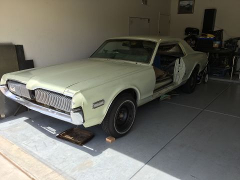 1968 Mercury Cougar - A 1968 Mercury Cougar is undergoing restoration in a garage, with its driver's side door removed.
