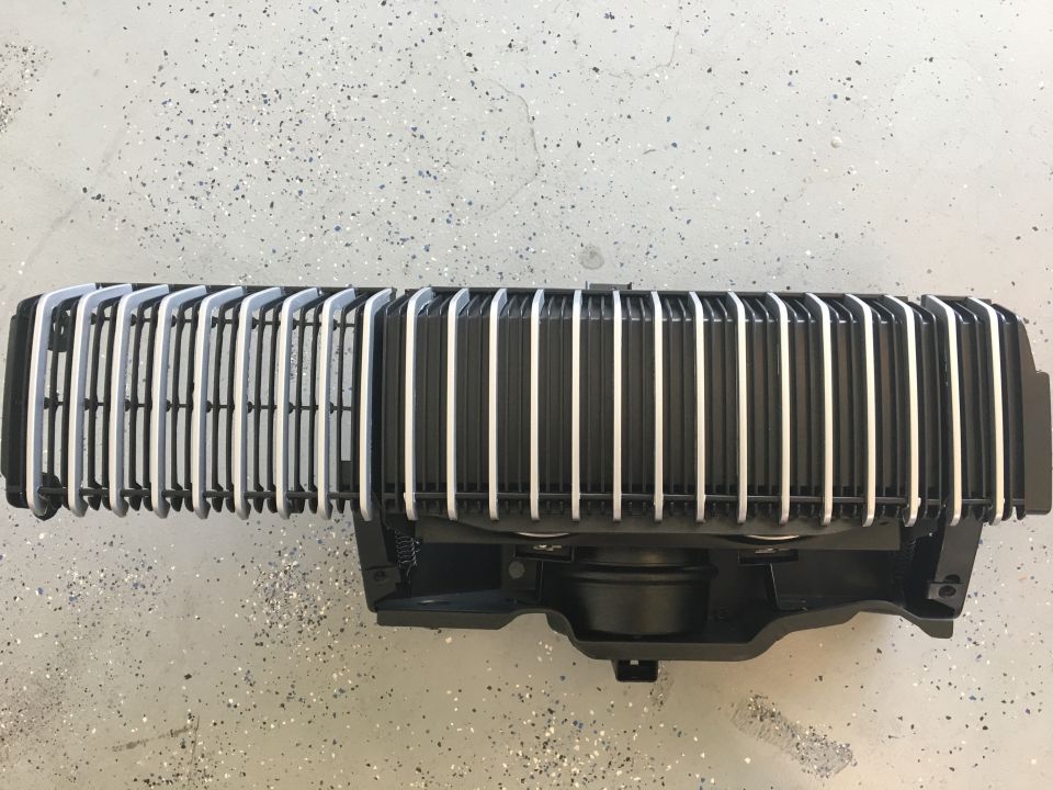 Black vertical-bar Cougar grille assembly with headlight door hardware on speckled garage floor
