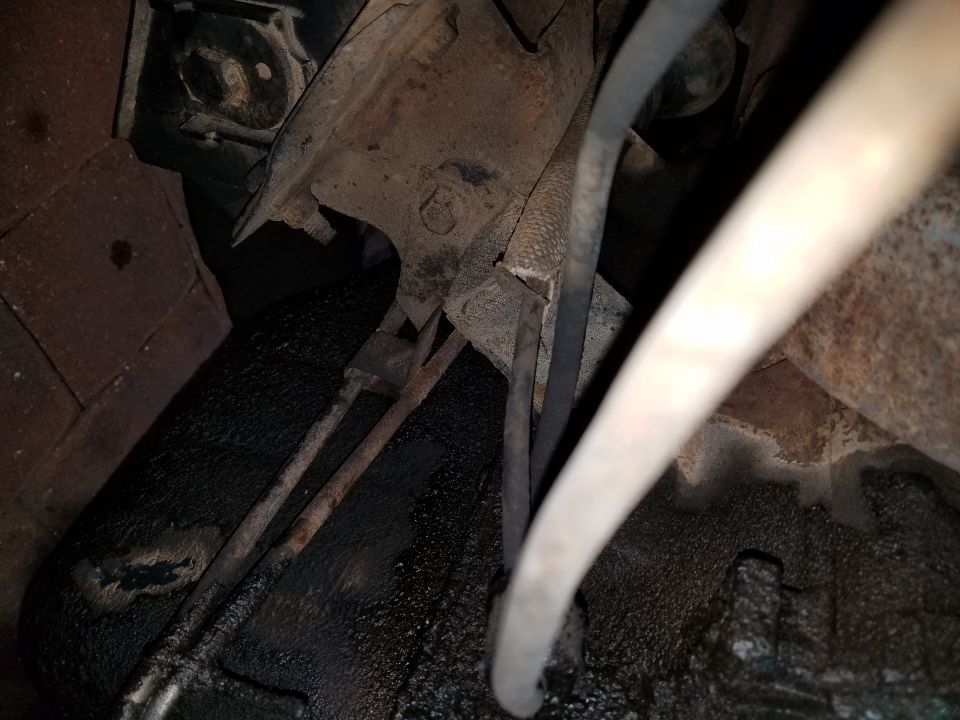 Close-up of rusty underbody components and hoses, possibly from a vintage car
