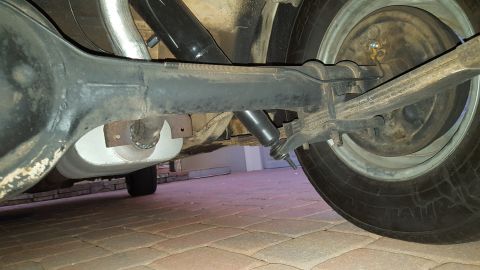 1971 Ford Mustang - Close-up of the rear suspension and axle assembly of a vehicle, showing the shock absorber and exhaust pipe.