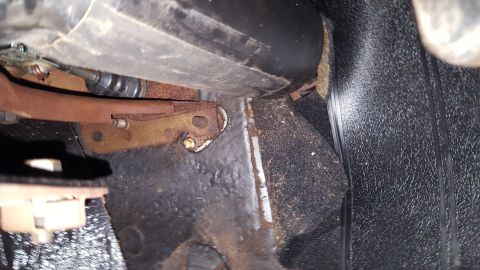 1971 Ford Mustang - This photo shows the floor area of a vehicle, focusing on a rusty bracket and carpeted surface.