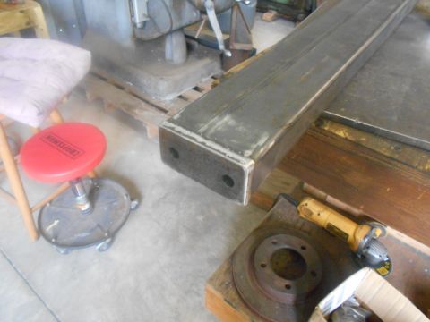 1992 Ford Bronco - Workshop scene with a large metal beam, grinder, and brake rotor on a wooden surface.