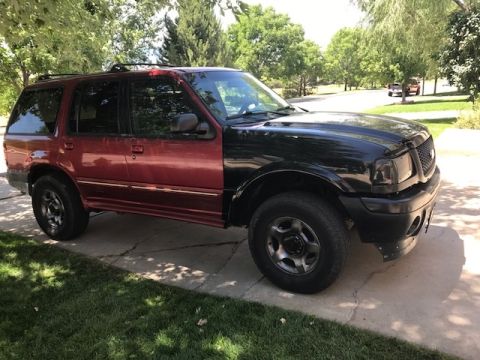 2000 Ford Explorer - This SUV has a red rear half and a black front half, with the front grille appearing to be from a 2000 model year vehicle.