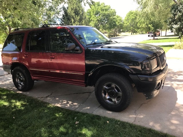 Red and black SUV with mismatched front end. Front grille suggests 2000 model year