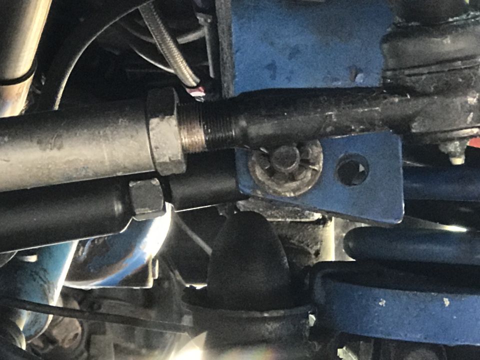 Close-up of vehicle steering linkage with blue painted bracket and silver tie rod
