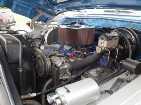 1967 Ford F-250 - Close-up of the engine bay, showing an aftermarket air filter and AC compressor, with another vehicle in the background.
