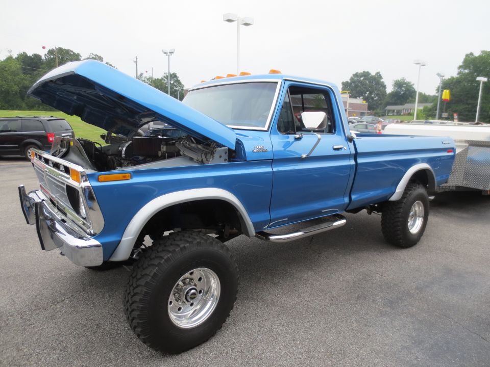 Blue Ford pickup truck with hood open, towing a trailer