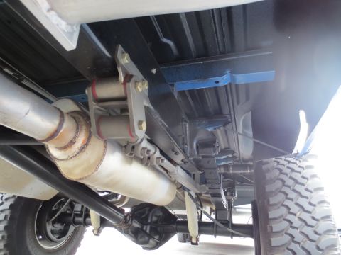1967 Ford F-250 - Close-up view of the rear suspension and exhaust system of a modified pickup truck.