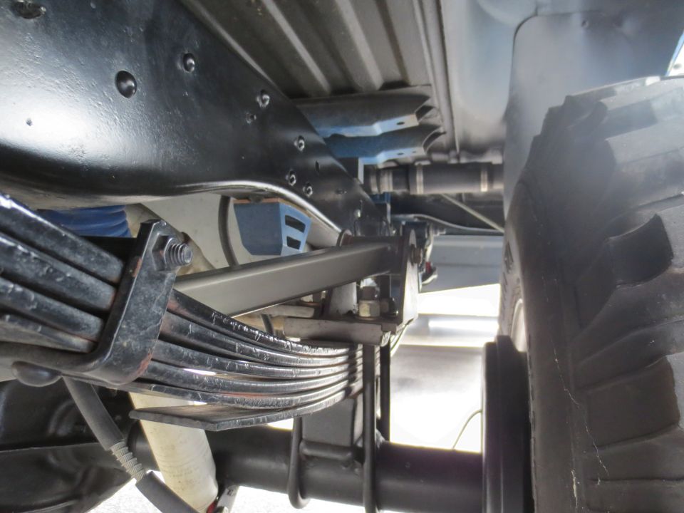 Truck leaf spring suspension and frame, viewed from below. The vehicle is dark colored