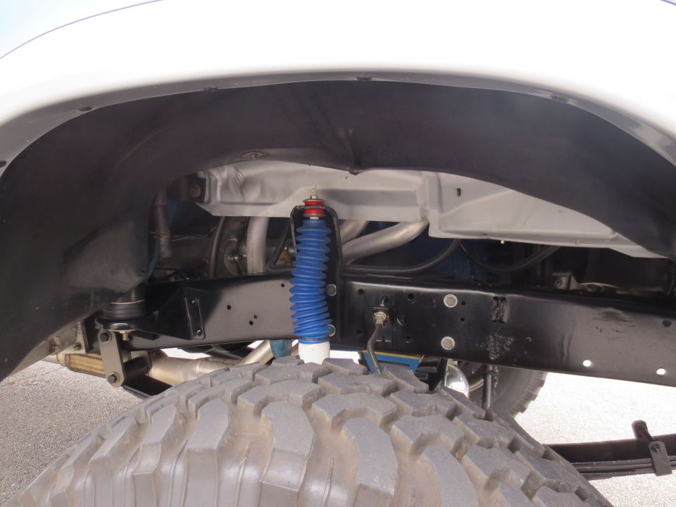 Close-up of a large truck tire and suspension components, including a blue shock absorber