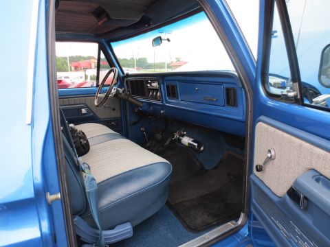 1967 Ford F-250 - The interior of a blue 1977 Ford F-150 pickup truck features a bench seat and a blue dashboard.