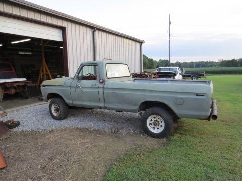 1967 Ford F-250 - Side view of a gray pickup truck parked outside a workshop with other vehicles visible.