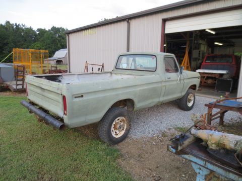1967 Ford F-250 - A light green Ford F-Series truck sits in front of a garage with a red truck inside.