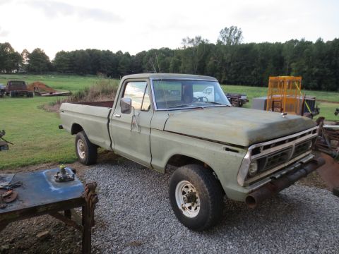 1967 Ford F-250 - This 1973 Ford F-Series pickup truck is seen in a rural setting with other vehicles in the background.