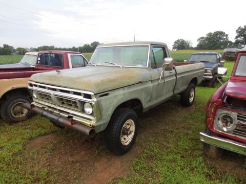 1967 Ford F-250 - A weathered green Ford F-Series truck sits in a field with other vehicles nearby.