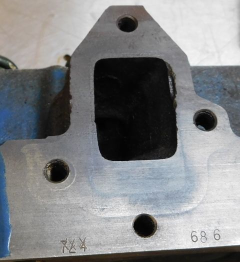 1968 Mercury Cougar - A metal engine part, possibly an intake manifold, shows stamped markings and a rectangular opening.