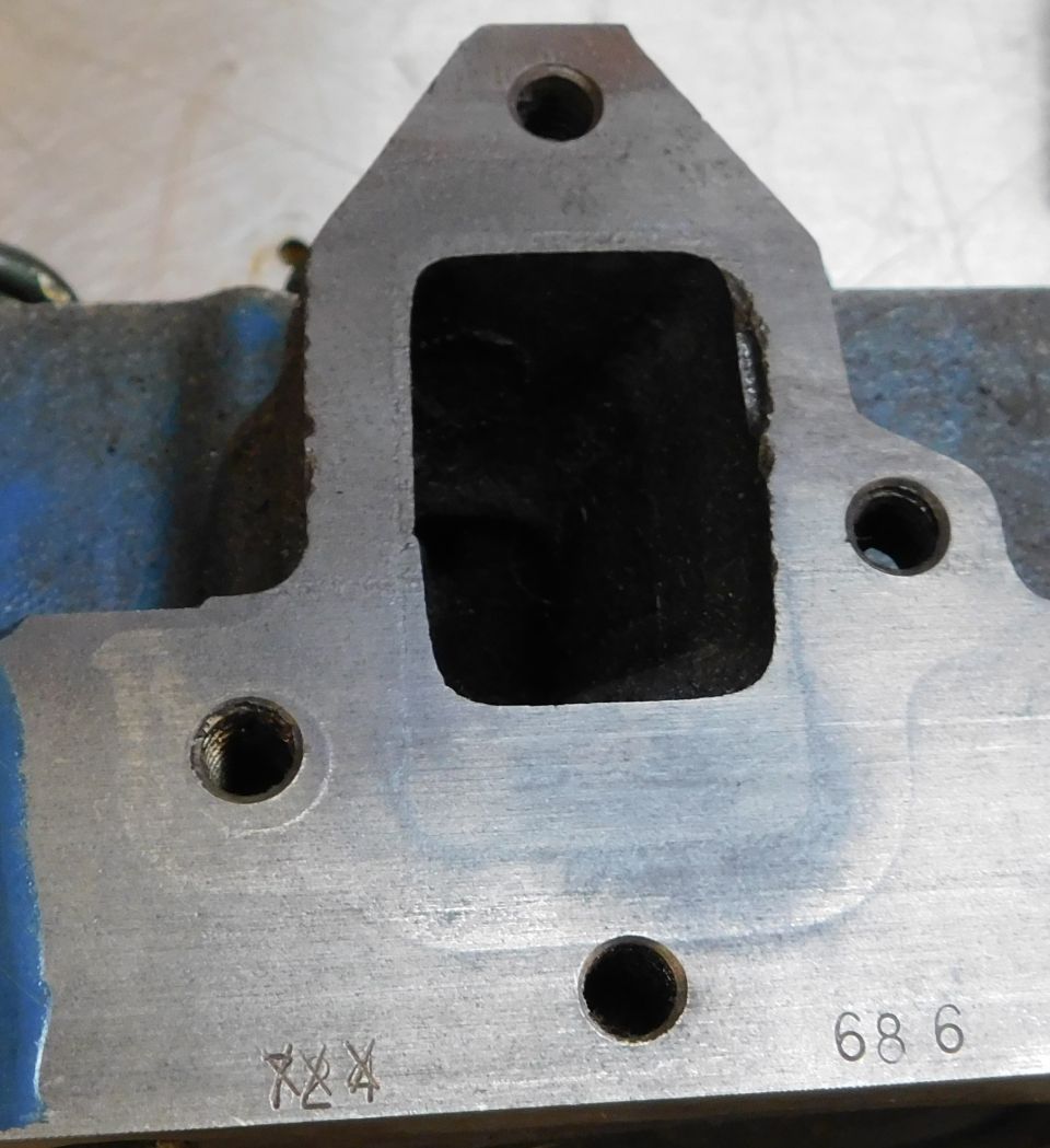 Close-up of an engine intake manifold part with stamped numbers '686' and 'XX4'