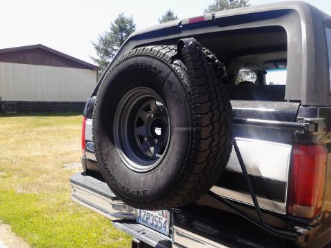1995 Ford Bronco - The rear of a vehicle shows a spare tire mounted externally, with a license plate visible below.