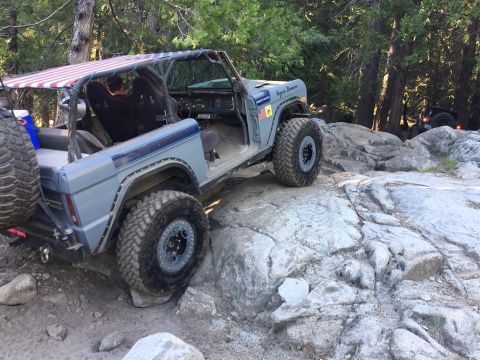 1979 Ford Bronco - This modified 1979 Ford Bronco navigates a rocky trail, its custom roof displaying an American flag pattern.