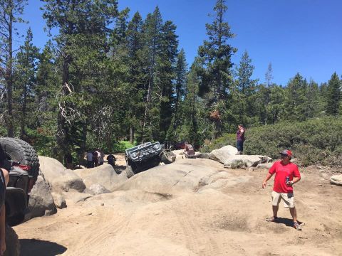 1979 Ford Bronco - A group watches as an off-road vehicle navigates a rocky trail on a sunny day.