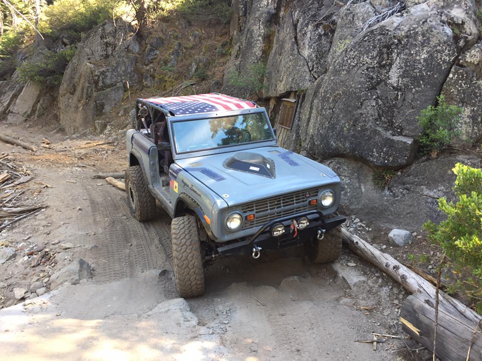 Gray Ford Bronco with American flag roof on a rocky trail