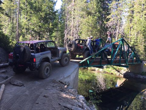 1979 Ford Bronco - A modified 1979 Ford Bronco navigates a challenging off-road trail, crossing a narrow bridge with other vehicles.