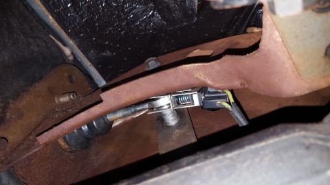 1971 Ford Mustang - Close-up of a vehicle's rusty clutch linkage mechanism, showing a spring and wiring.