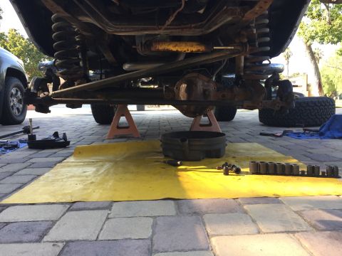 1978 Ford Bronco - Vehicle undercarriage work in progress, showing suspension and drivetrain components. Tools are laid out on a yellow mat.