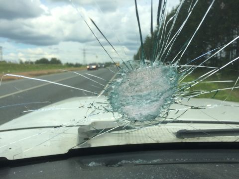 1993 Ford Bronco - Windshield damage from inside the vehicle, with a highway visible through the cracks.