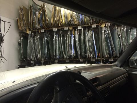 1993 Ford Bronco - View from inside a vehicle shows a storage area filled with automotive windshields.
