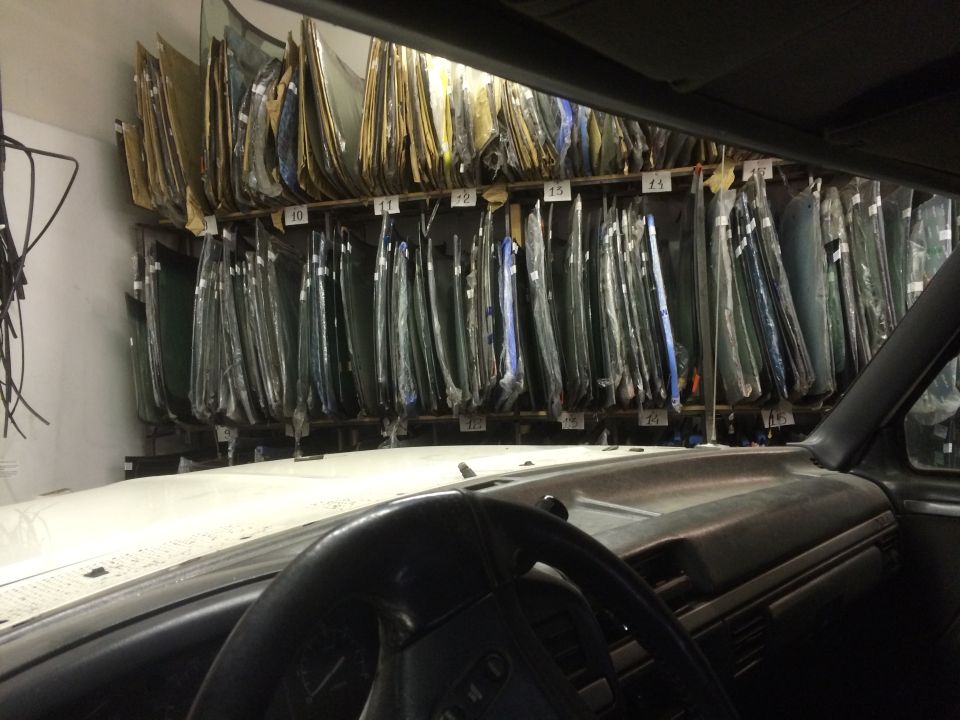 Car interior looking out at rows of windshields on racks