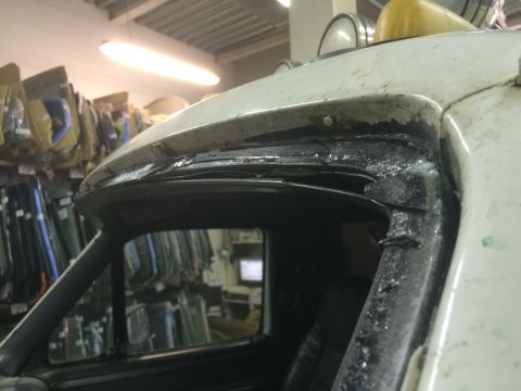 1993 Ford Bronco - Close-up of a damaged windshield frame on a white vehicle, showing deteriorated sealant.