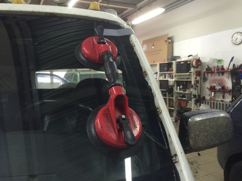 1993 Ford Bronco - Suction cups are being used to remove the windshield of a vehicle in a workshop.