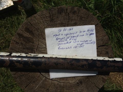 1993 Ford Bronco - A napkin with handwritten text is placed on a wooden stump, with a metal pipe in the foreground.