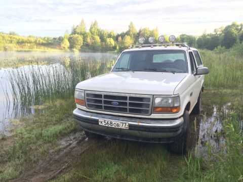 1993 Ford Bronco - White 1993 Ford Bronco sits by the water's edge on a cloudy day.