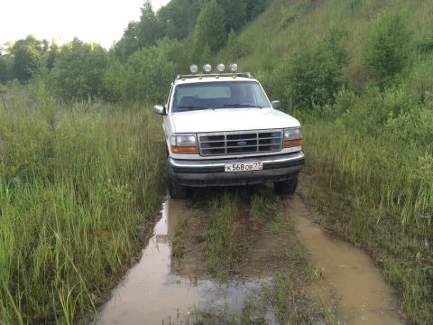 1993 Ford Bronco - This 1993 Ford Bronco navigates a muddy path surrounded by tall grass and trees.