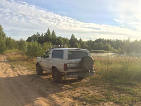 1993 Ford Bronco - White 1993 Ford Bronco parked on a dirt road with a lake in the background.