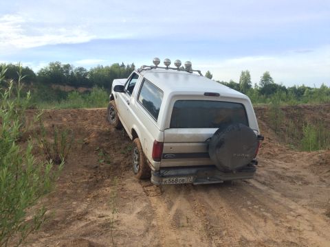 1993 Ford Bronco - White 1993 Ford Bronco navigates a dirt path with a spare tire mounted on the rear.