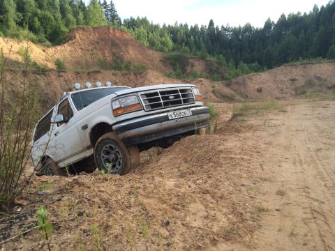 1993 Ford Bronco - White 1993 Ford Bronco navigating a dirt track with steep inclines.