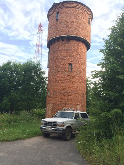 1993 Ford Bronco - A 1993 Ford Bronco is parked on a dirt road next to a tall brick water tower.
