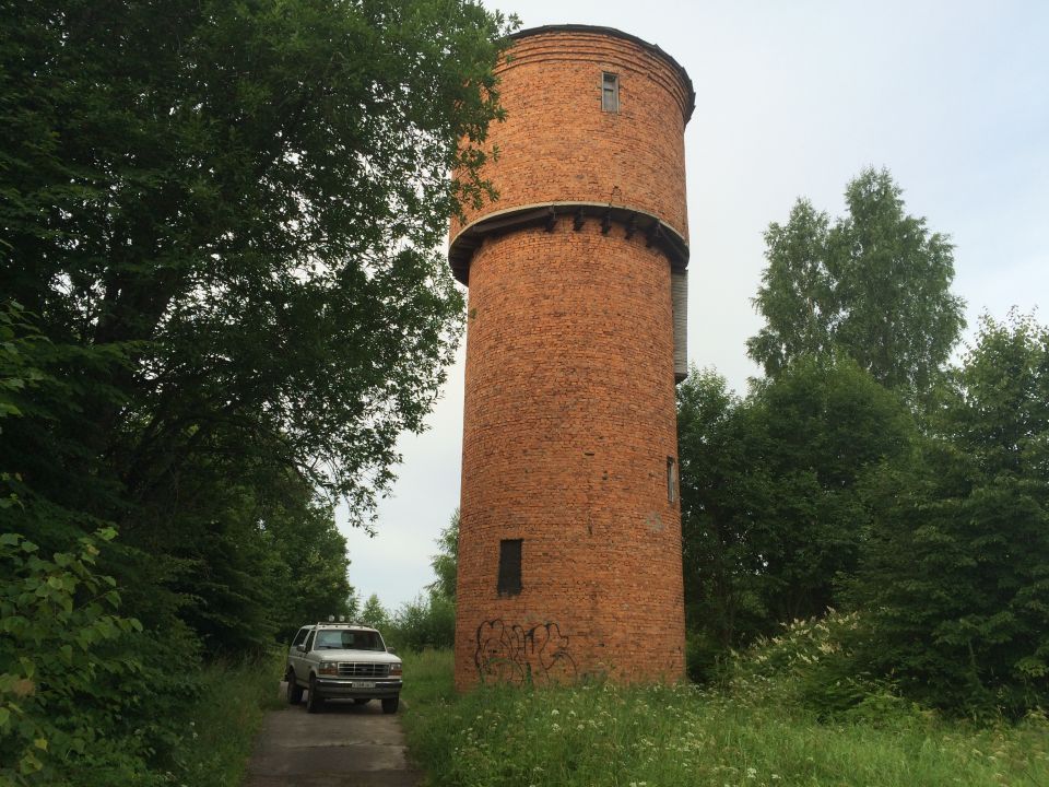 Silver Ford Bronco parked on dirt road by brick water tower