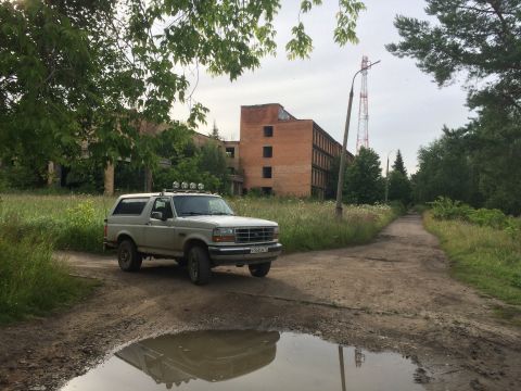 1993 Ford Bronco - 1993 Ford Bronco on a dirt road near an abandoned building.
