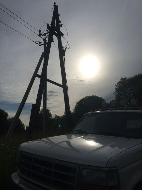 1993 Ford Bronco - White SUV with roof lights parked near a utility pole under a hazy sun.