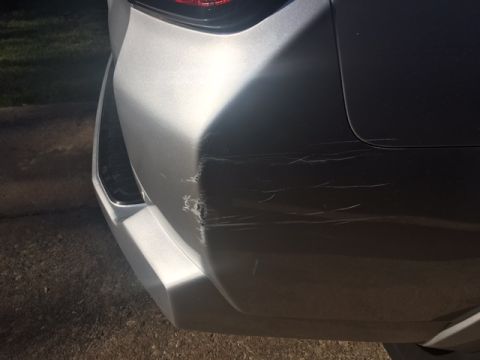 2004 Ford F-150 - The rear bumper of a silver vehicle shows extensive scratching and impact damage on the right corner.
