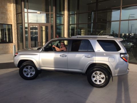 2004 Ford F-150 - A silver SUV is parked in front of a modern building with large glass windows, and a person is visible in the driver's seat.