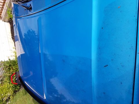 1995 Ford Bronco - Bright blue vehicle hood with a red tow hook on the side.