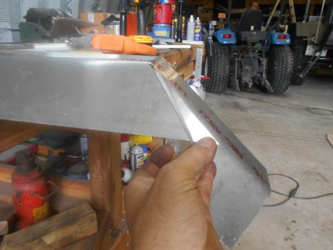1992 Ford Bronco - A hand works on shaping an aluminum panel in a workshop, with a tractor visible in the background.