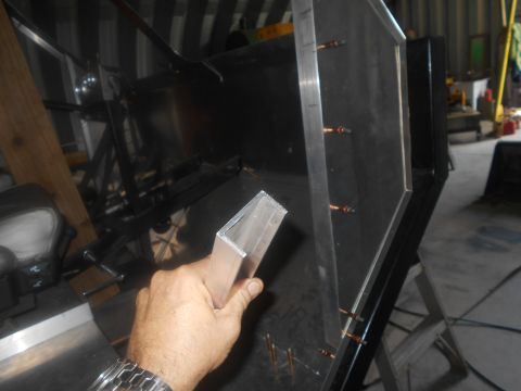 1992 Ford Bronco - A person is holding a piece of aluminum angle iron near a dark metal panel with visible copper rivets.