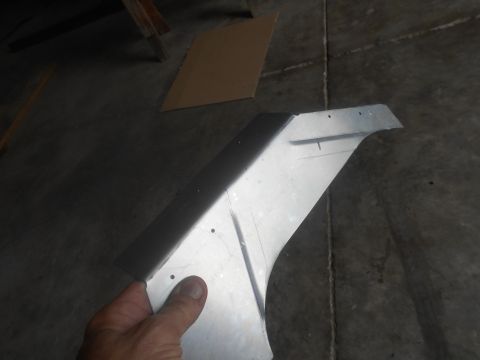 1992 Ford Bronco - A metal car fender part is held up for inspection, showing fabrication marks.