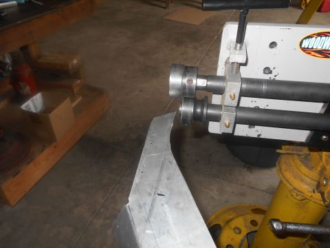 1992 Ford Bronco - A metal part is being formed on a Wood-worker roller in a workshop setting.